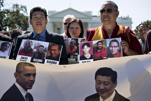 People hold up photos of alleged victims of persecution during a protest in front of the White House ahead of the upcoming state visit of Chinese President Xi Jinping September 16, 2015 in Washington, DC. AFP PHOTO/BRENDAN SMIALOWSKI