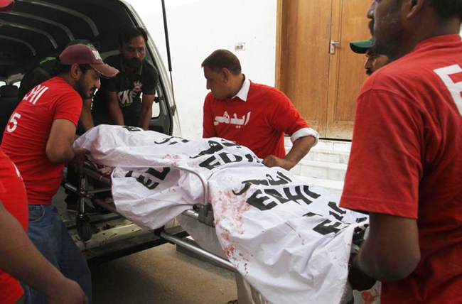 FILE - In this Wednesday, Sept. 9, 2015 file photo,volunteers load the dead body of  Pakistani journalist, Aftab Alam, who was killed by unknown gunmen, into an ambulance at a local hospital in Karachi, Pakistan. In the last quarter century, at least 2,297 journalists and media staff have been killed. And ever more, killers act with impunity, the International Federation of Journalists announced in a major report.(AP Photo/Fareed Khan, File)
