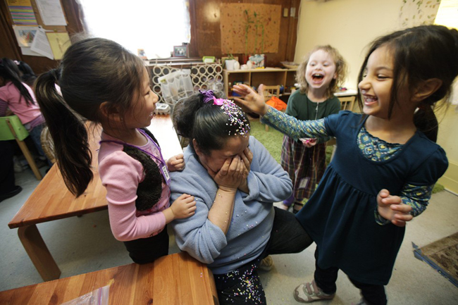 In this April 5, 2012, photo, pre-school teacher Sandra Medina, center, is showered with a confetti egg with students Lyvia Pham, left, 4, Howra Aljumaili, 5, right, and Molly Kiniry, 4, rear right,  at the Refugee and Immigrant Family Center in Seattle. Washington state preschool programs that receive government dollars are among the best in the country but too few kids benefit from the $54 million the state spends on preschool each school year, according to a report released Tuesday, April 10, 2012. (AP Photo/Ted S. Warren)