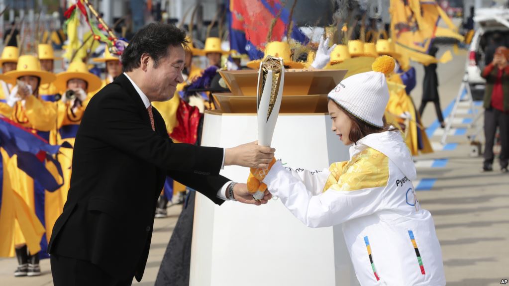 South Korean Prime Minister Lee Nak-yon, left, passes the Olympic torch to torch bearer, South Korean figure skater You Young, right, at Incheon bridge in Incheon, South Korea, Wednesday, Nov. 1, 2017. The Olympic flame arrived in South Korea on Wednesday where it will be passed throughout the country by thousands of torchbearers on a 100-day journey to the opening ceremony of the 2018 Winter Olympics in Pyeongchang. (AP Photo/Lee Jin-man)