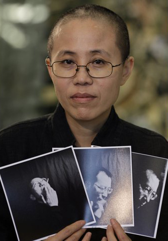 Liu Xia, the wife of Chinese dissident Liu Xiaobo, holds photos of Liu Xiaobo during an interview in Beijing October 3, 2010. Chinese dissident Liu Xiaobo is tipped to win the 2010 Nobel Peace Prize, according to a leading bookmaker, as the Nobel Committee seeks to restore its authority after criticism of the 2009 pick of U.S. President Barack Obama. REUTERS/Petar Kujundzic (CHINA - Tags: POLITICS)