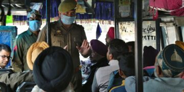 Indian police man wearing surgical masks and talk to passangers for aware for coronavirus at screening camp in lakhanpur 92 kms from Jammu, India, Wednesday, March.4, 2020. Rohit Kansal, Jammu and Kashmir Principal Secretary informed that no positive case has been reported and entire administrative machinery, including health machinery is in full alert. "21 suspected cases have been tested so far and no positive case has been reported so far across Jammu and Kashmir.(AP Photo/Channi Anand)