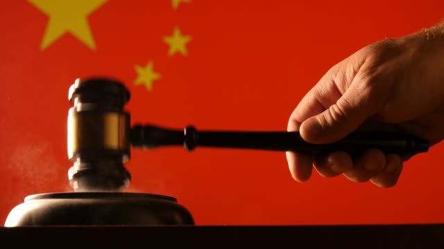 Judge hammer and gavel with Chinese flag background in a court of law that is used for judgement legislation and government juridical systems.