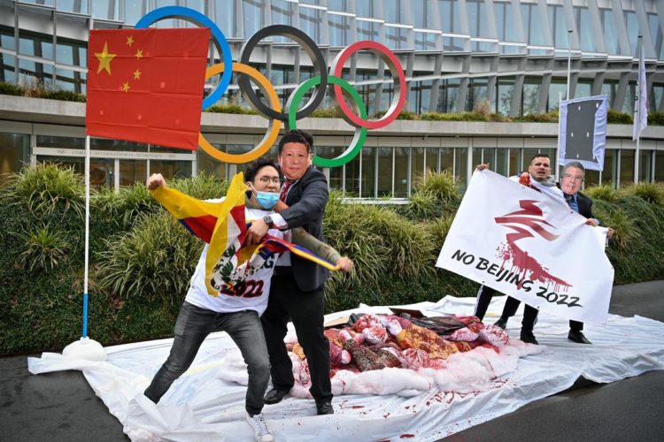 Protesters with masks bearing Chinese President Xi Jinping (2ndL) and International Olympic Committee (IOC) President Thomas Bach (R) pretend to pretend to fight with activists during a protest against Beijing 2022 Winter Olympics, staged by activists of the International Tibet Network, on February 3, 2021 in front of the IOC headquarters in Lausanne. - A coalition of campaign groups issued an open letter calling on world leaders to boycott the Beijing 2022 Winter Olympics over China's rights record. The Games are scheduled to begin on February 4 next year, just six months after the delayed summer Tokyo Olympics, but preparations have been overshadowed by the coronavirus pandemic. (Photo by Fabrice COFFRINI / AFP) (Photo by FABRICE COFFRINI/AFP via Getty Images)