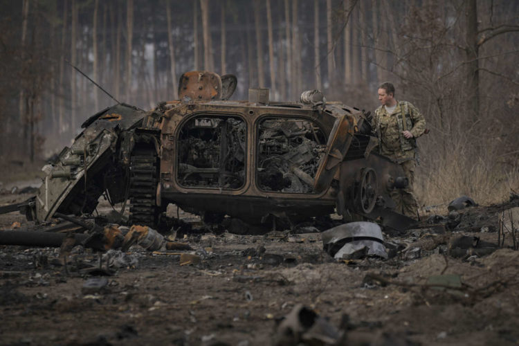 A Ukrainian soldier inspects a destroyed Russian armored transport vehicle outside Kyiv on March 31. (Vadim Ghirda/AP)