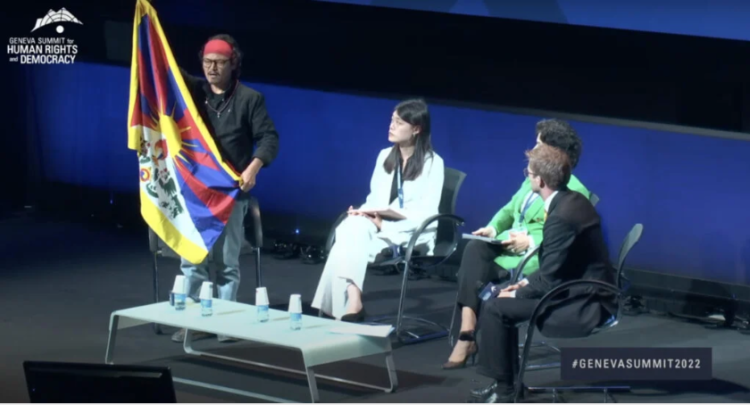 Poet and freedom activist Tenzin Tsundue unfurling a Tibetan national flag at the summit.
