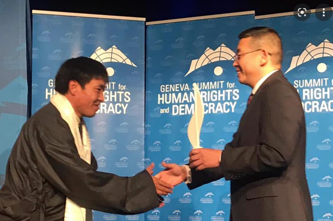 Tibetan filmmaker Dhondup Wangchen receives the prestigious Courage Award from the Chinese dissident and former political prisoner Yang Jianli on Mar 27. (Photo courtesy: Geneva Summit)