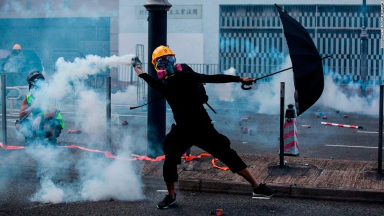 A protester throws back a tear gas canister fired by police in Hong Kong on October 1, 2019. CNN IMAGES