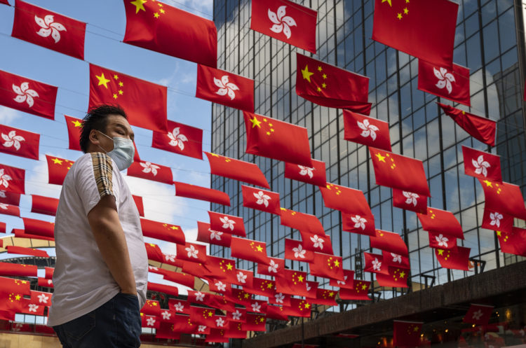 A pedestrian waits to cross the street as flags of the People's Republic of China and the Hong Kong SAR are displayed ahead of July 1st anniversary of Hong Kong's handover to China in Hong Kong. (Photo by Miguel Candela / SOPA Images/Sipa USA)No Use Germany.