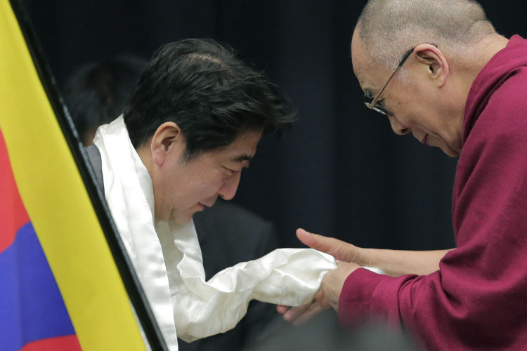 Tibetan spiritual leader the Dalai Lama, right, gives a white Tibetan scarf to Japan's main opposition Liberal Democratic Party President Shinzo Abe during a seminar held by Japanese Diet members in Tokyo, 13 November 2012.