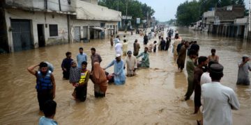Displaced people wade through a flooded area in Peshawar, Khyber Pakhtunkhwa, Pakistan on Saturday.