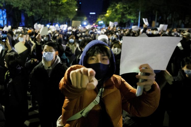 People hold white sheets of paper in protest against COVID-19 restrictions in Beijing on Sunday. | REUTERS