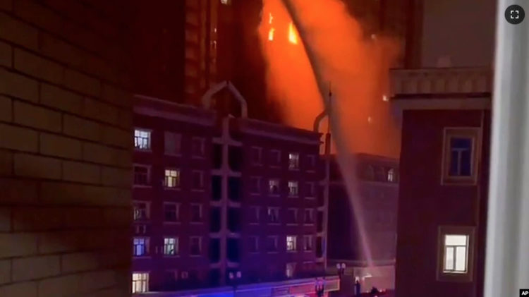 In this image from video, crews spray water on a fire at a residential building in Urumqi in western China's Xinjiang Uyghur Autonomous Region, Nov. 24, 2022.