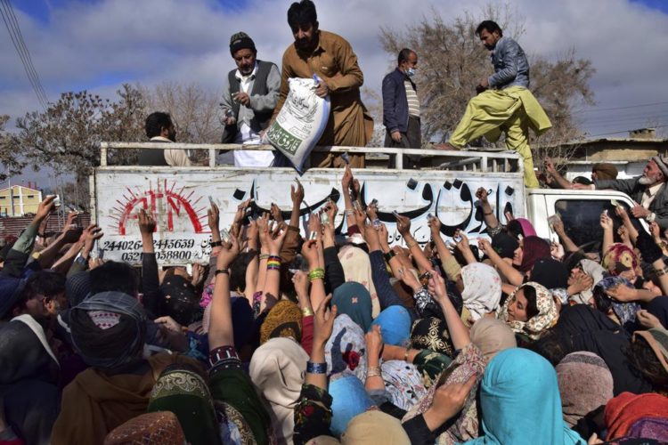 People jostle each other to buy subsidized sacks of wheat flour in Quetta, Pakistan, Thursday, Jan. 12, 2023