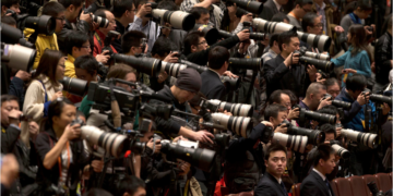 A Chinese security official looks back at rows of journalists covering a plenary session of the National People's Congress in Beijing in March 2013. (Ng Han Guan/AP)