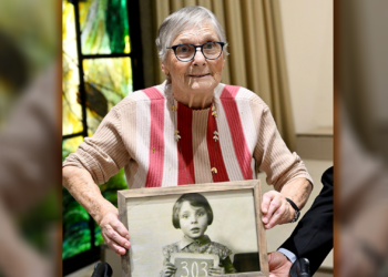  Holocaust and October 7 survivor Mirjam Beit Talmi Szpiro holding a photo of herself as a 3-year-old in Amsterdam, 1939, on the way to Britain