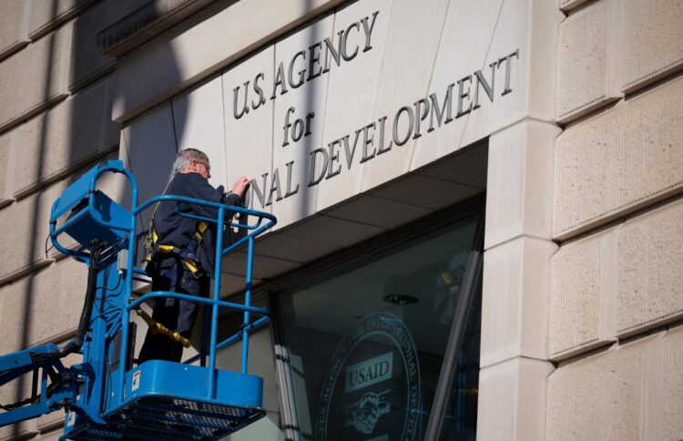 A worker removes the U.S. Agency for International Development sign on their headquarters on Feb. 07, 2025 in Washington, D.C.