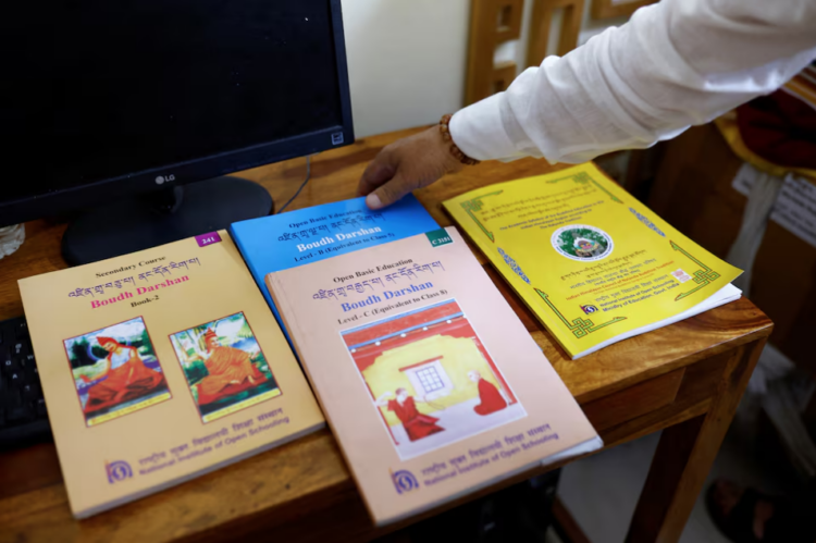 A man shows books that are part of the new school curriculum for Buddhist monasteries at the office of Indian Himalayan Council of Nalanda Buddhist Tradition (IHCNBT) in New Delhi, India, March 13, 2025. REUTERS/Anushree Fadnavis