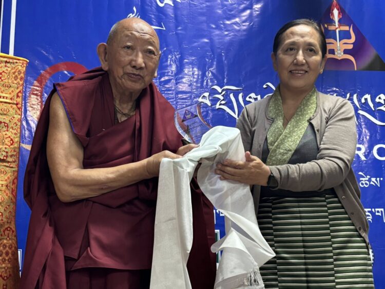 བོད་མིའི་སྒྲིག་འཛུགས་ཀྱི་ཆེས་མཐོའི་ཁྲིམས་ཞིབ་ཁང་གི་ཁྲིམས་ཞིབ་པ་ཆེ་བ་ཡེ་ཤེས་དབང་མོ་མཆོག་གིས་ཤེས་བྱའི་རྩོམ་སྒྲིག་པ་ཟུར་པ་དང་དགའ་ལྡན་ཕོ་བྲང་གི་བོད་དྲུང་བྱམས་པ་བསྟན་འཛིན་མཆོག་ལ་སཾ་བྷོ་ཊ་བུམ་པའི་རྩོམ་སྒྲིག་གཟེངས་རྟགས་འབུལ་བཞིན་པ། བོད་ཀྱི་དུས་བབ་གསར་ཁང་གི་པར། ༢༠༢༥།༡༠།༦
